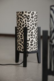 Eruca 34cm Leopard tischlampe Von Markslöjd - Der Lampenfu&szlig; aus schwarzem Holz wird mit einem zylindrischen Textilschirm in cremewei&szlig;em und braunem Leopardenmuster kombiniert, was der Lampe einen trendigen und individuellen Charakter verleiht.