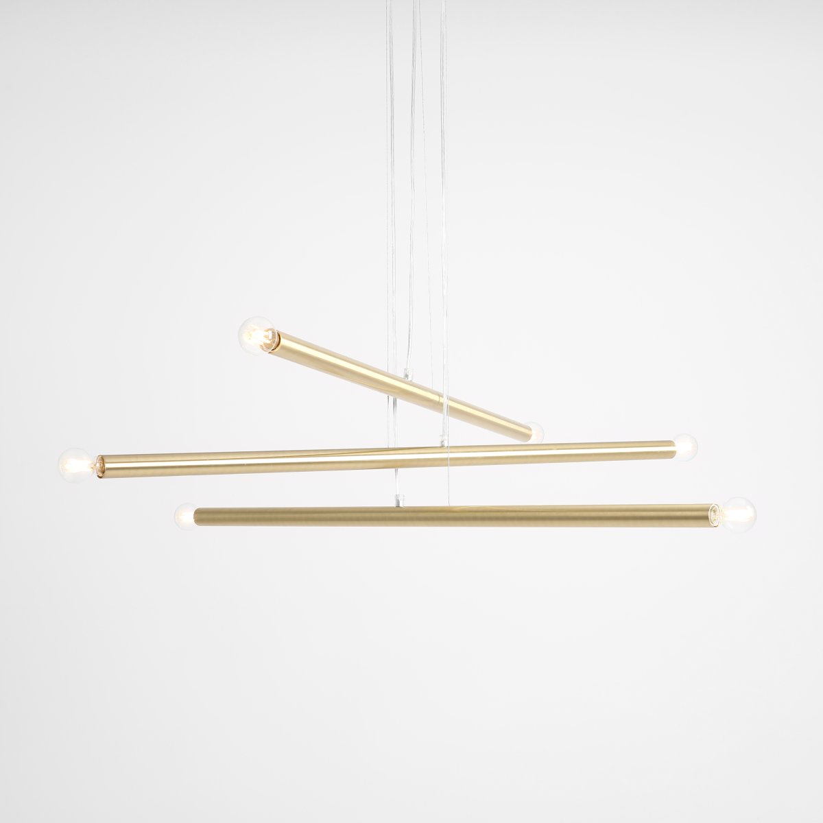 Tubo 6 100cm Messing hängelampe Von Artera - Die Leuchte besteht aus drei schmalen Metallröhren in elegantem Messing-Finish, die in unterschiedlichen Höhen und Winkeln angeordnet sind und so eine dynamische und luftige Optik erzeugen.