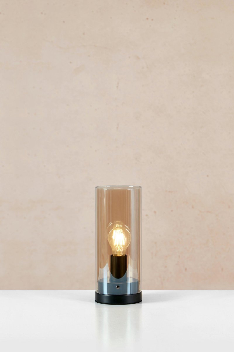 Post 38cm Bernstein tischlampe Von Markslöjd - Post ist eine stilvolle Tischlampe in Zylinderform mit einem Sockel aus mattschwarzem Metall und einem bernsteinfarbenen Glasschirm.