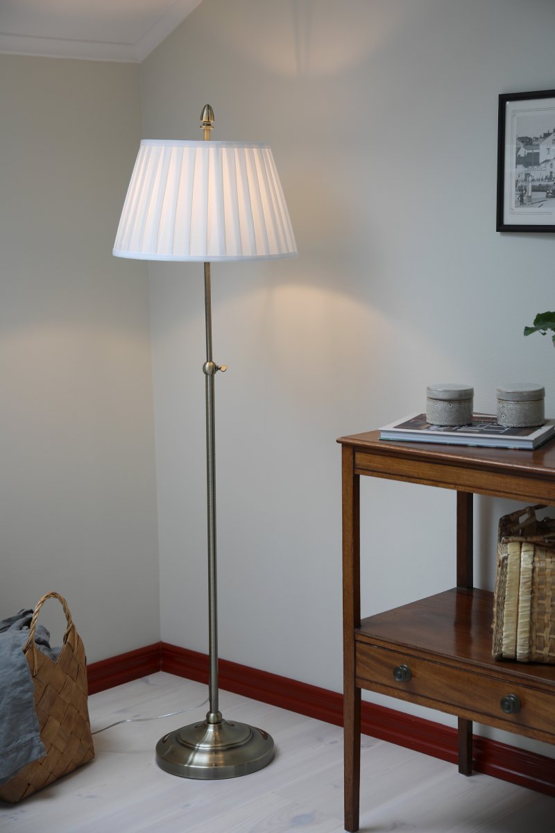Oxford Antikmessing stehlampe Von Markslöjd - Stehlampe im klassischen Stil der Jahrhundertwende mit cremefarbenem Textilschirm und Fuß in Antikmessing-Optik.