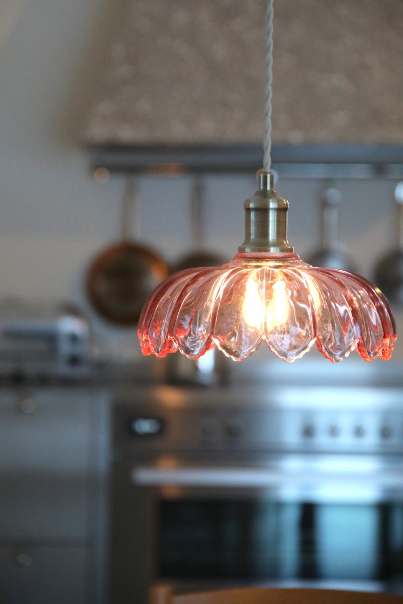 Kurage Ø26 Rosa hängelampe Von Markslöjd - Die Leuchte hat eine Fassung in Messingoptik und ein dekoratives, beigefarbenes Textilkabel, das zu einer runden Metallhalterung in derselben Messingoptik f&uuml;hrt.