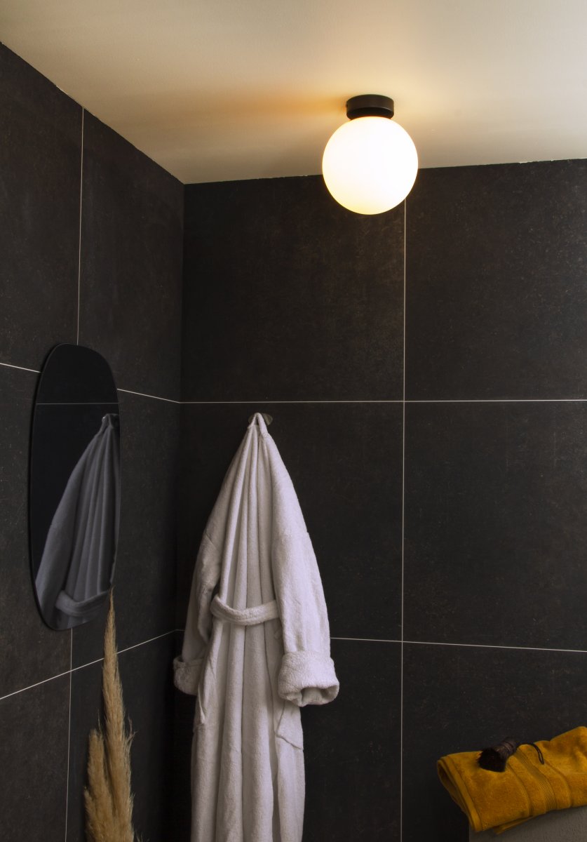 Lido Ø20 Schwarz badezimmerlampe Von Aneta Lighting - Der mattschwarze Metallrahmen wird mit einem runden Opalglasschirm kombiniert, der ein sanftes und angenehmes Licht verbreitet.