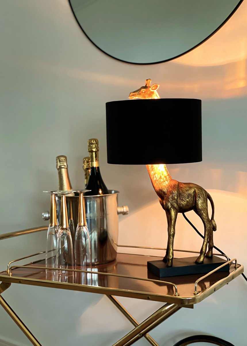 Affe 50cm Gold tischlampe Von Aneta Lighting - Affe-Tischleuchte mit schwarz lackiertem Metall-Lampenfu&szlig; und einer dekorativen goldfarbenen Giraffe, deren Kopf durch den Textilschirm ragt.