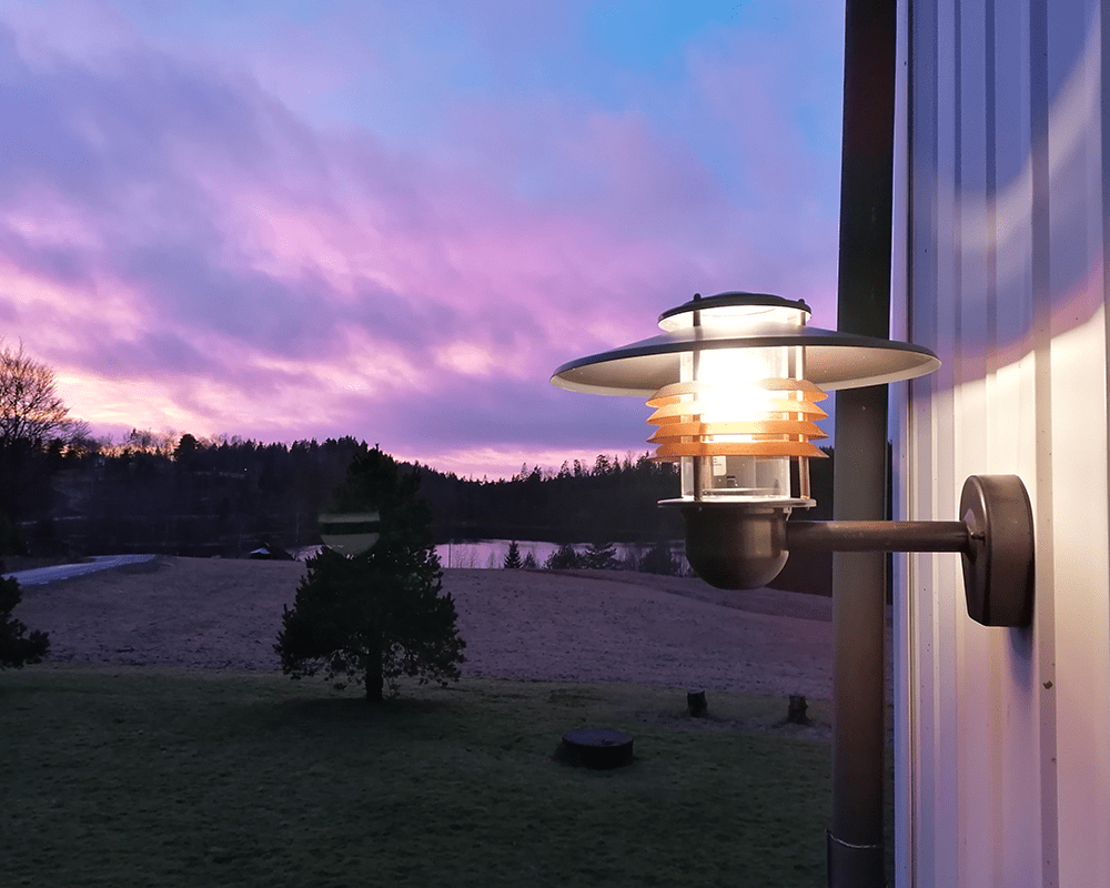 Arnäs Oxidiertes Kupfer außenlampe Von Westal - Arns Wandleuchte ist eine stilvolle Leuchte mit einem runden Lichtmuster und einem klaren Glasschirm, der die Lichtquelle umgibt.