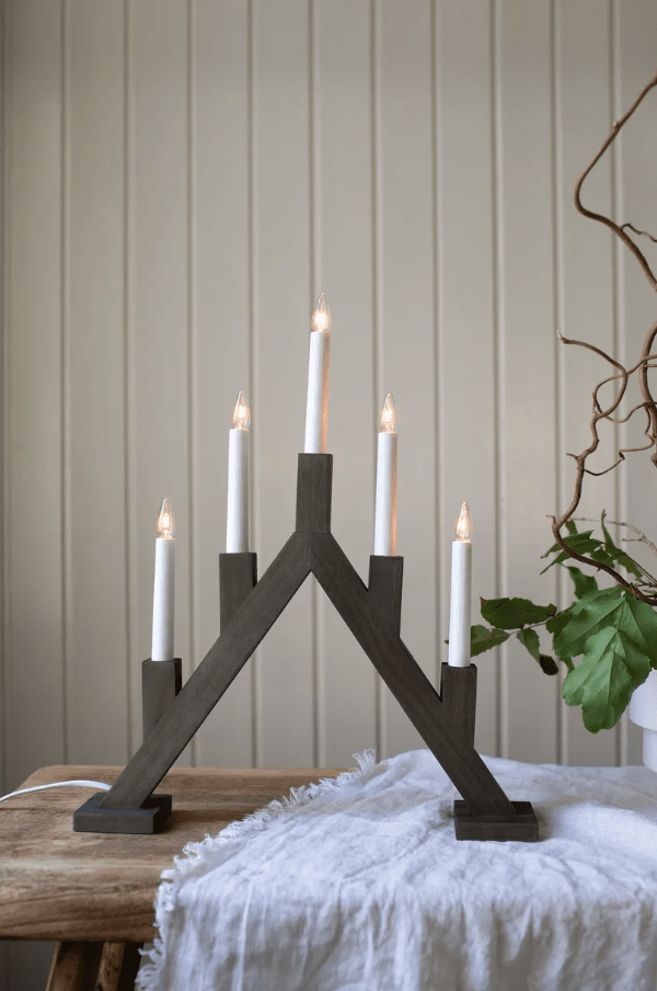 Bjurfors 5L Brauner Fleck Von Markslöjd - Der Kerzenst&auml;nder hat einen Sockel aus dunkel gebeiztem Holz und f&uuml;nf wei&szlig;e Kerzen, die einen sch&ouml;nen Kontrast bilden.