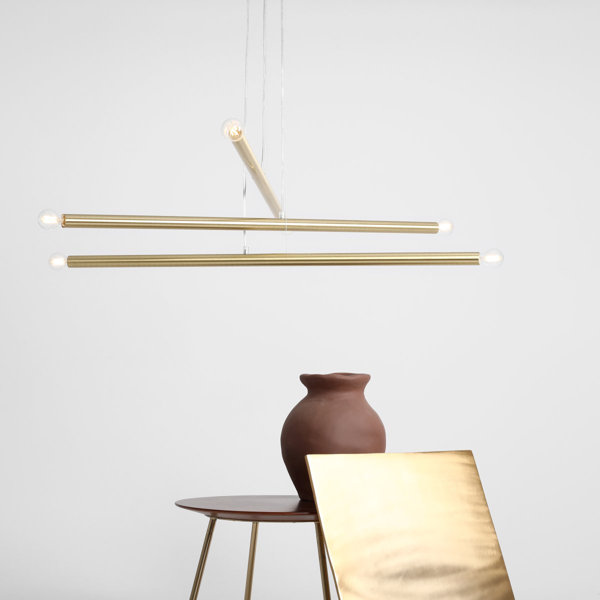 Tubo 6 100cm Messing hängelampe Von Artera - Die Leuchte besteht aus drei schmalen Metallröhren in elegantem Messing-Finish, die in unterschiedlichen Höhen und Winkeln angeordnet sind und so eine dynamische und luftige Optik erzeugen.