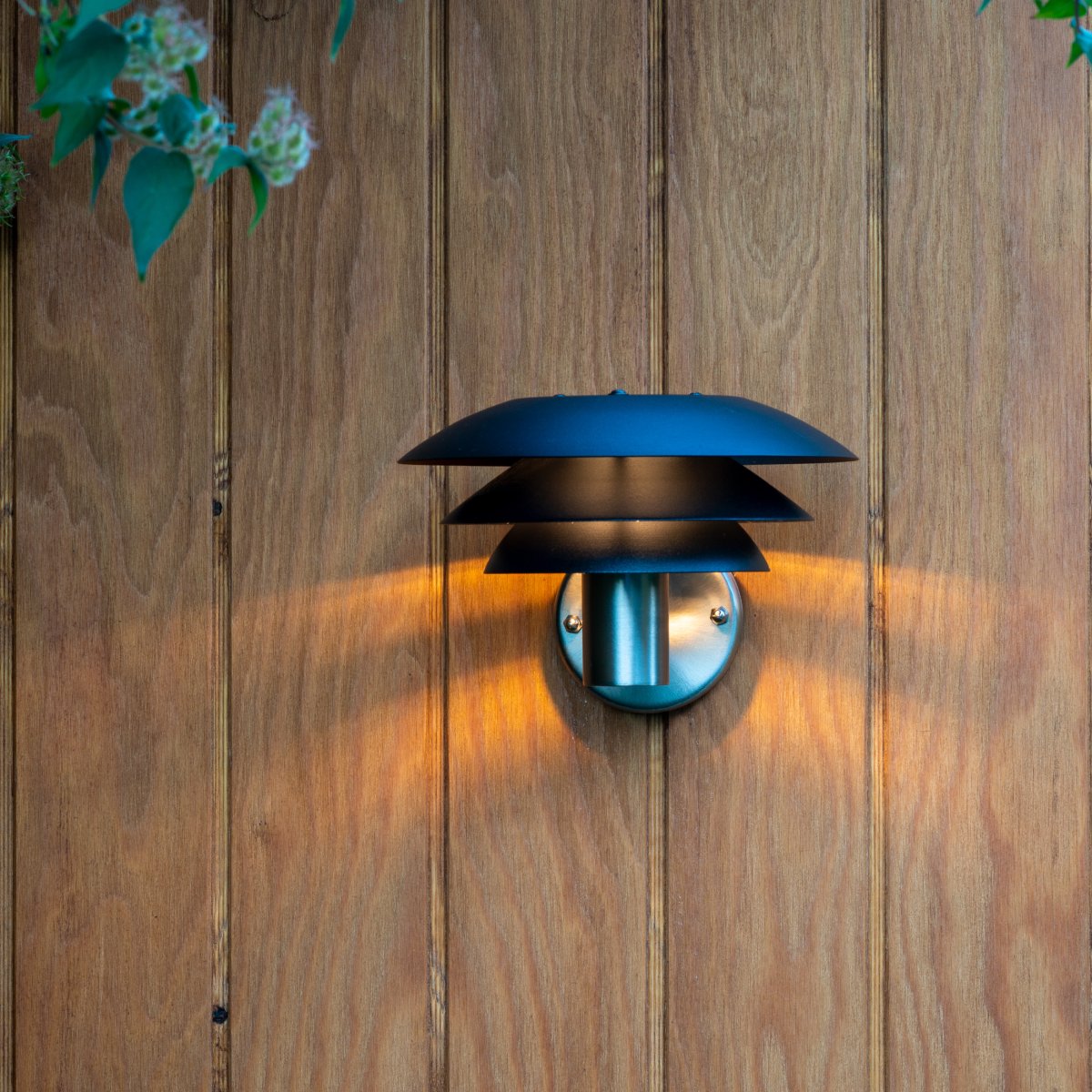 DL20 Edelstahl außenlampe Von Dyberg Larsen - Die Lampe verfügt über drei ikonische Schirme in unterschiedlichen Größen, die ein magisches Licht verbreiten und ist aus Edelstahl mit eleganten mattschwarzen Schirmen gefertigt.