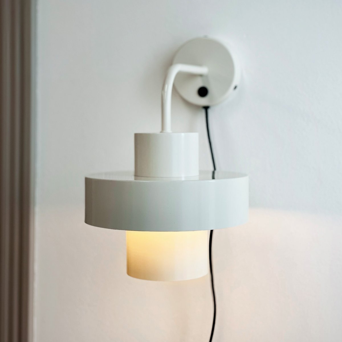 Stoke Ø15 Weiß wandlampe Von Dyberg Larsen - Sie besteht aus Metall mit einer glänzenden Oberfläche, die die zylindrischen Formen der Lampe hervorhebt und einen ausgewogenen Kontrast zu anderen Materialien wie Stein, Holz und Glas bildet.