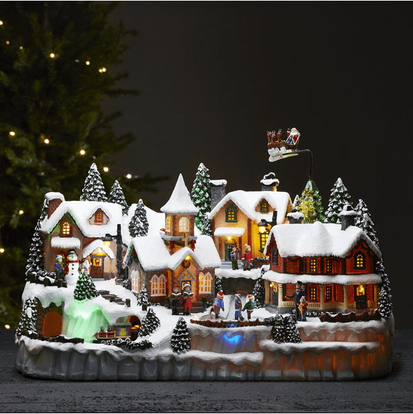 Largeville Mehrfarbig Von Star Trading - Gro&szlig;e und detailreiche Weihnachtsdekoration in Form eines Dorfes mit drei verschiedenen rotierenden Teilen: Eisenbahn, Schlittschuhlaufende Kinder, Rentier mit Schlitten und Weihnachtsmann.