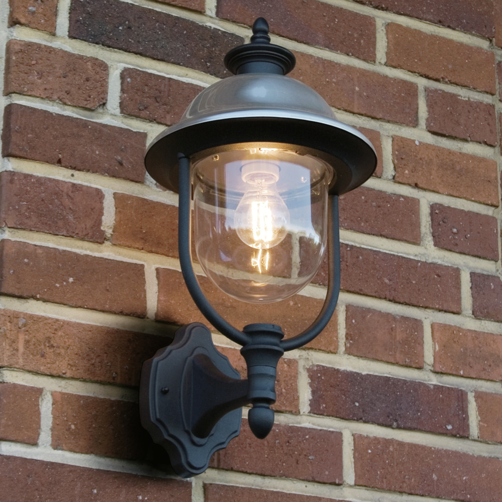 Parma Schwarz außenlampe Von Konstsmide - Mit seiner robusten schwarzen Oberfläche und dem klaren Glasschirm verbreitet es ein warmes und einladendes Licht und schafft so eine einladende Atmosphäre am Eingang oder auf der Terrasse.