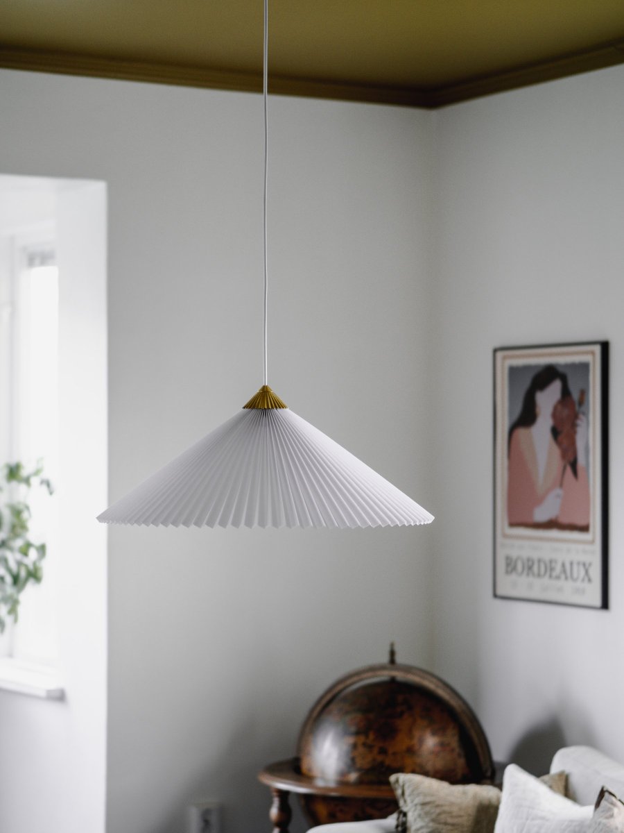 Matisse Ø60 Weiß hängelampe Von Globen Lighting - Die Lampe hat einen plissierten weißen Textilschirm und ist mit einem dazu passenden plissierten Oberteil aus messingfarbenem Metall verziert.