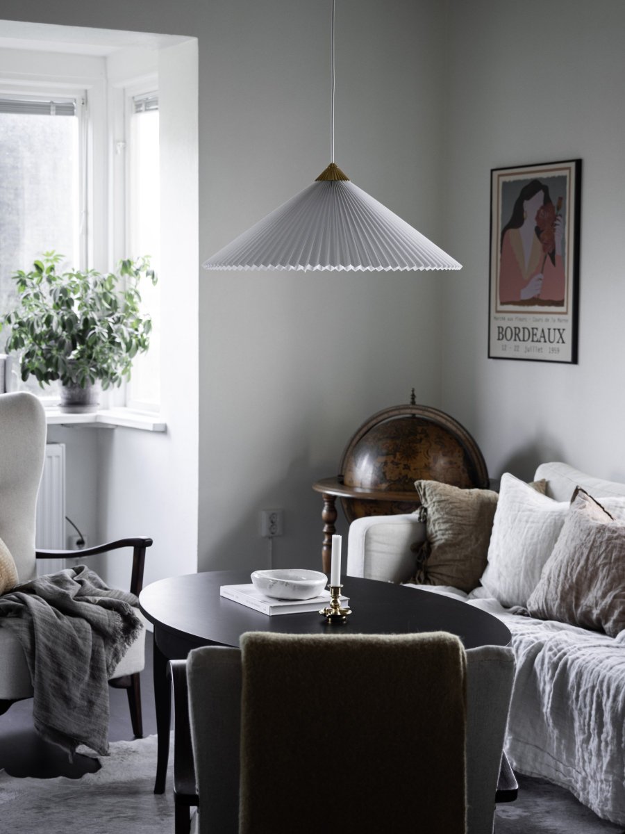 Matisse Ø60 Weiß hängelampe Von Globen Lighting - Die Lampe hat einen plissierten weißen Textilschirm und ist mit einem dazu passenden plissierten Oberteil aus messingfarbenem Metall verziert.