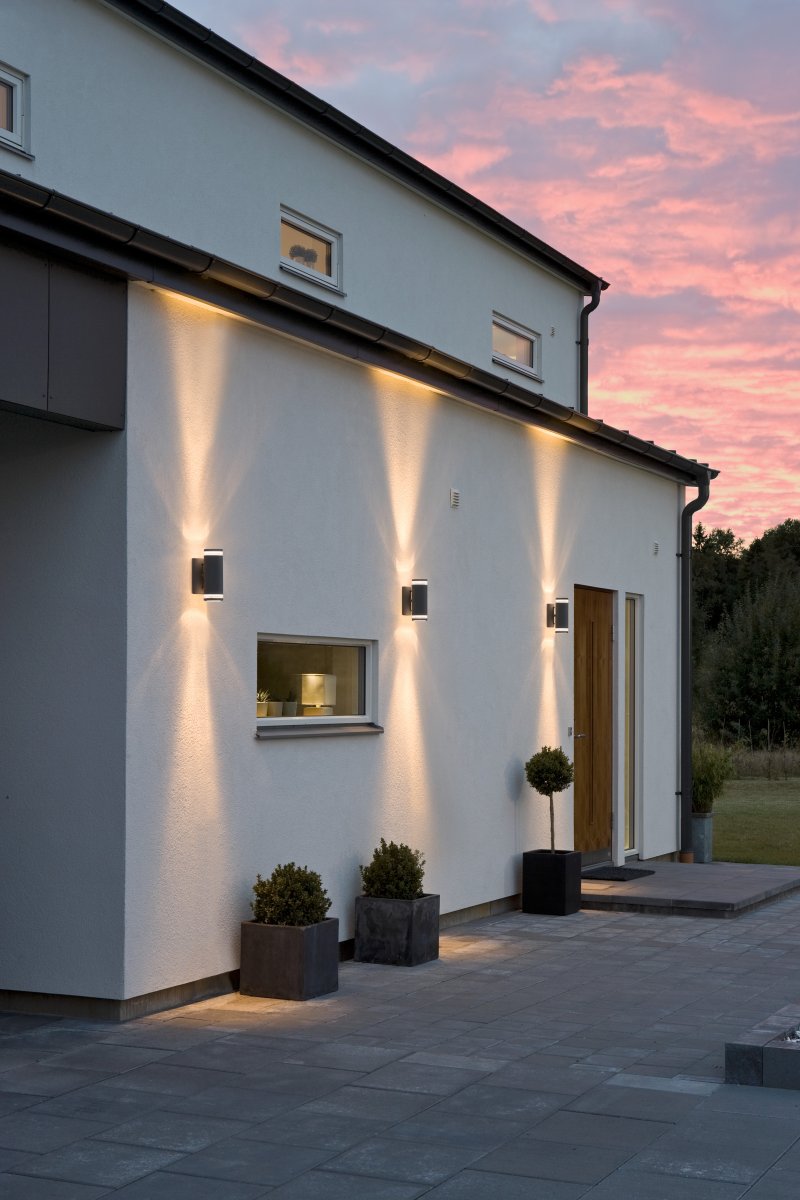 Modena II Schwarz außenlampe Von Konstsmide - Das Licht wird sowohl nach oben als auch nach unten gerichtet und erzeugt ein dekoratives und wirkungsvolles Lichtbild, das die Fassade aufwertet und dem Garten eine einladende Atmosph&auml;re verleiht.
