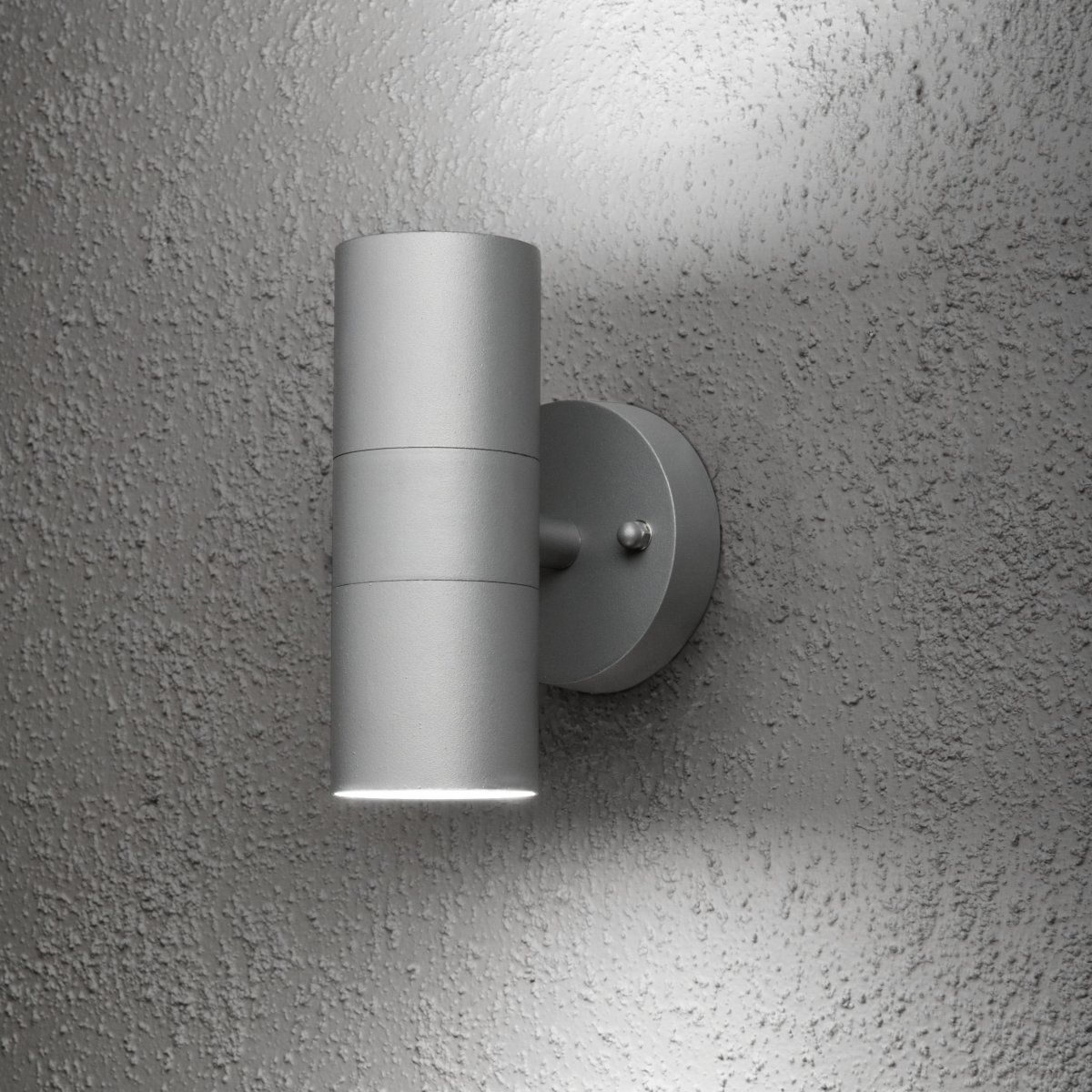 Modena Grau außenlampe Von Konstsmide - Die Leuchte strahlt das Licht sowohl nach oben als auch nach unten ab und erzeugt ein dekoratives Lichtbild, das die Fassade hervorhebt und eine einladende Atmosph&auml;re im Au&szlig;enbereich schafft.