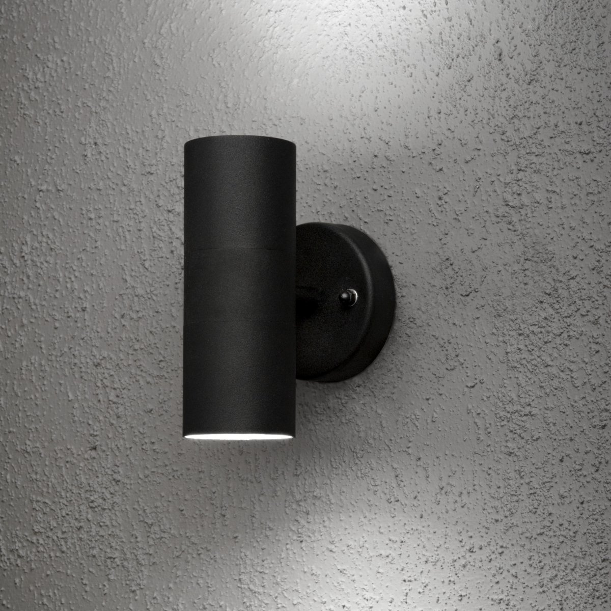 Modena Schwarz außenlampe Von Konstsmide - Die Leuchte strahlt das Licht nach oben und unten ab und erzeugt ein dekoratives Lichtbild, das die Fassade hervorhebt und eine einladende Atmosph&auml;re im Au&szlig;enbereich schafft.