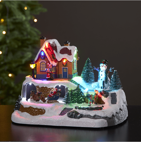 Winterville Mehrfarbig Von Star Trading - Eine sch&ouml;ne Weihnachtsdekoration mit einem Schneemann, der die eislaufenden Kinder beobachtet, und dem Weihnachtsmann mit Schlitten und Rentieren.