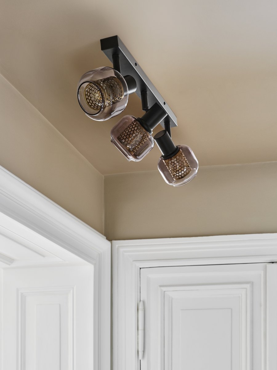 Firefly 3 Schwarz spotlight Von Osram - De r&ouml;rliga spotlightsen med sk&auml;rmar av gr&aring;tonat glas i kombination med de guldiga detaljh&ouml;ljet som omfamnar ljusk&auml;llorna bidrar med en elegans till rummet.