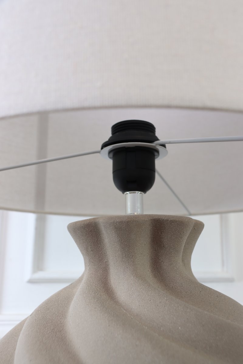 Vindel 52cm Sand tischlampe Von Lampan - Der Keramikfu&szlig; besticht durch seine sandfarbene, strukturierte Oberfl&auml;che und ein sanft geschwungenes Design, das ihm eine lebendige und skulpturale Ausstrahlung verleiht.