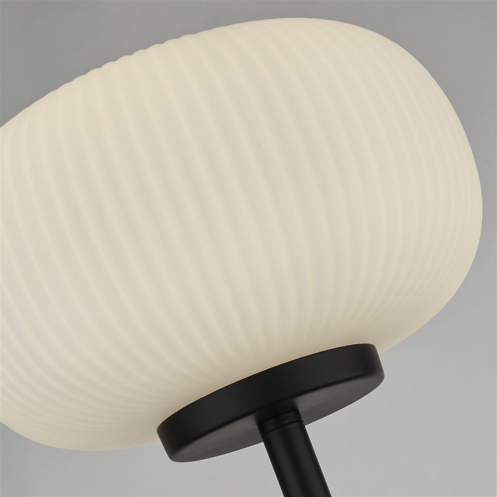 Lumina Schwarz stehlampe Von Searchlight - Die Stehleuchte Lumina kombiniert einen mattschwarzen Metallrahmen mit geriffeltem Opalglas – ein Kontrast, der ein modernes und elegantes Gefühl vermittelt.