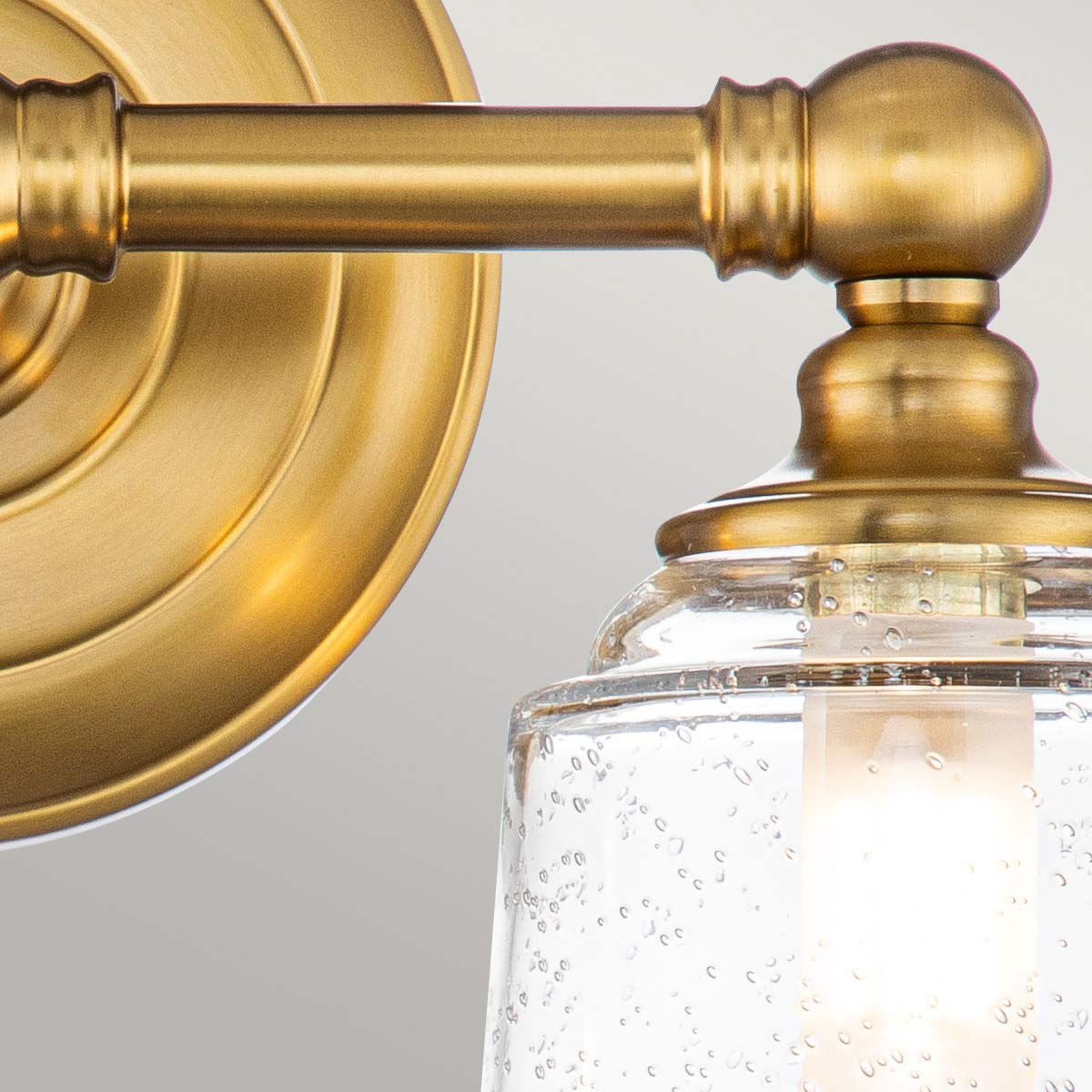 Huguenot Lake 33cm Messing badezimmerlampe Von Elstead Lighting - Die eleganten runden Details und die handgeschliffenen Fassungen vermitteln ein Gefühl traditioneller Handwerkskunst, während das klare, strukturierte Glas ein weiches und einladendes Licht erzeugt.