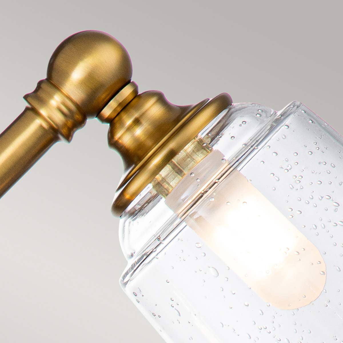 Huguenot Lake 53cm Messing badezimmerlampe Von Elstead Lighting - Die eleganten runden Details und die handgeschliffenen Fassungen vermitteln ein Gefühl traditioneller Handwerkskunst, während das klare, strukturierte Glas ein weiches und einladendes Licht erzeugt.