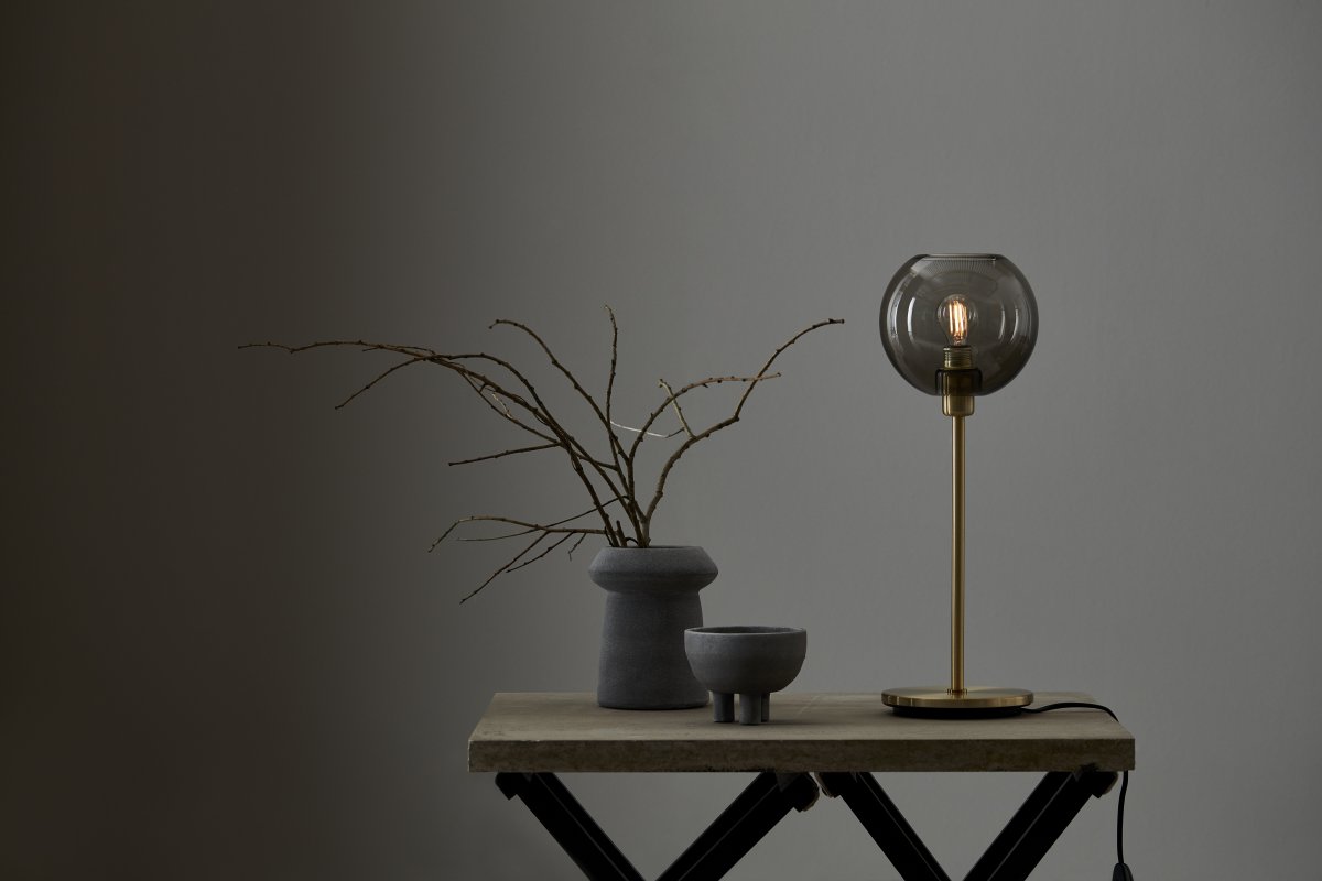 Gloria 46cm Messing/Rauch tischlampe Von Belid - Gloria hat ein einfaches und elegantes Design mit einem Lampensockel aus Metall und einem runden Glasschirm.