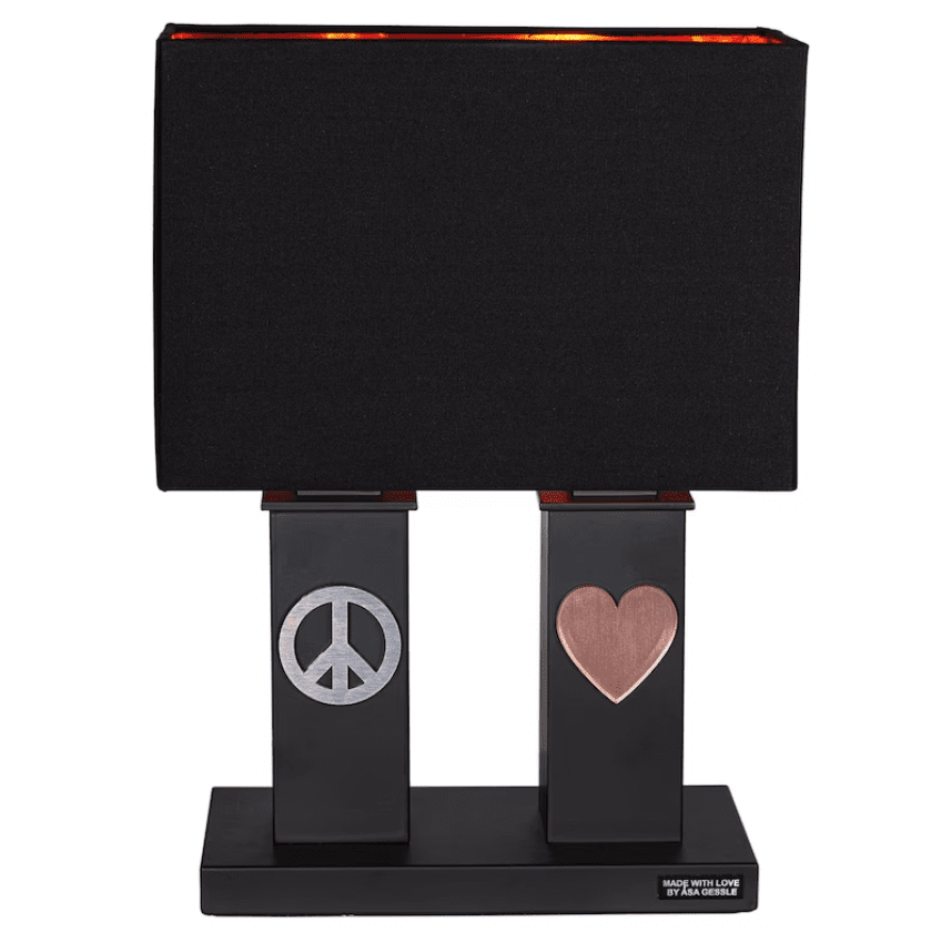 Stand By Me 50cm Schwarz tischlampe Von By Rydéns - Der breite, schwarze Stofflampenschirm harmoniert im Kontrast mit den schmaleren S&auml;ulen des Lampenfu&szlig;es, die beide mit einem Metallsymbol verziert sind, auf der einen Seite dem Peace-Zeichen, auf der anderen einem Herz.